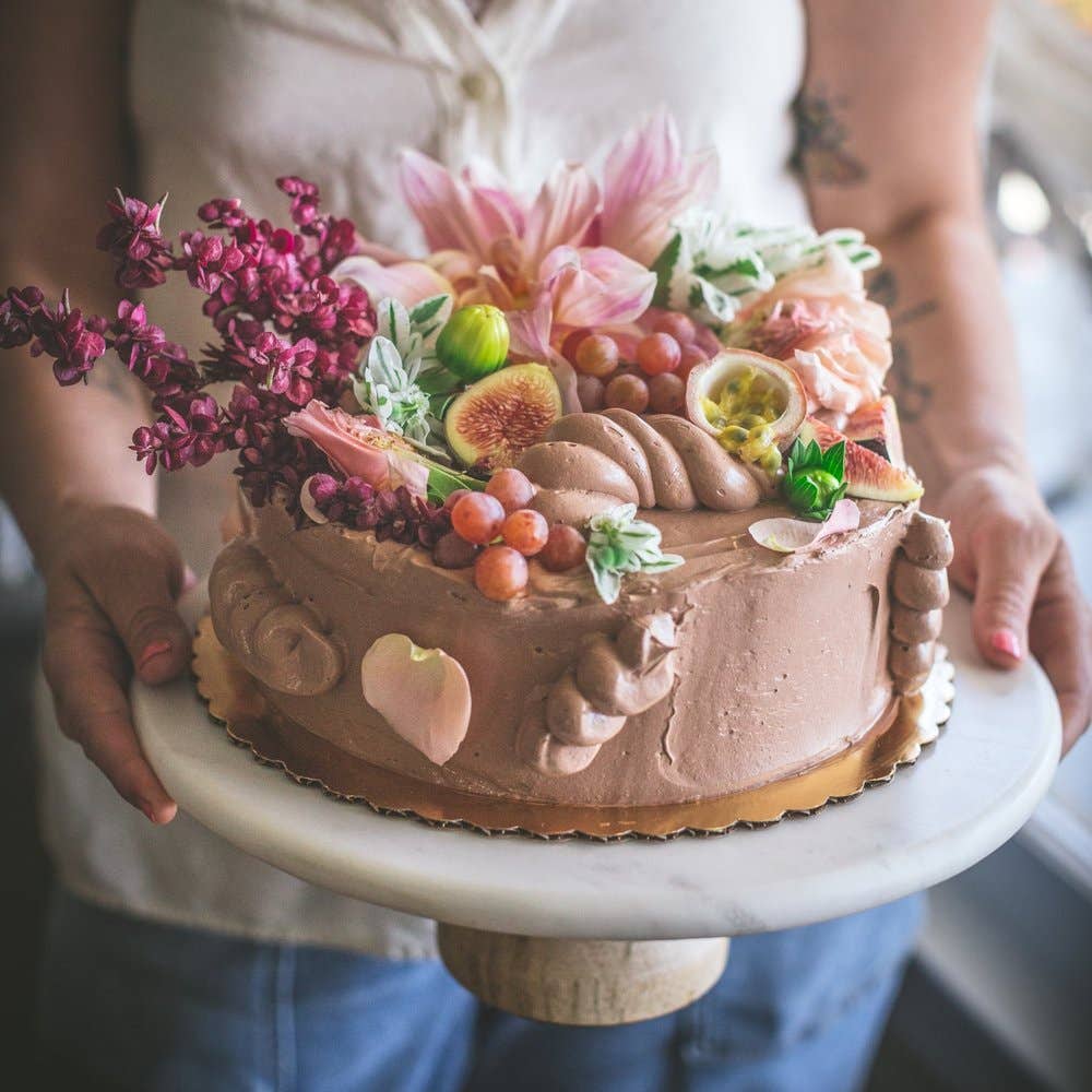 Baker holding cake with flowers on it